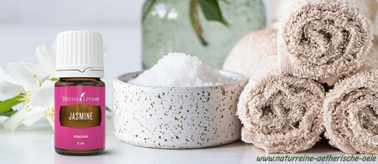 Jasmine Absolue von Young Living neben Badesalz, weißen Blüten und gerollten Handtüchern